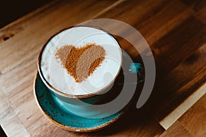 Cup of cappuccino coffee decorated cinnamon heart symbol.