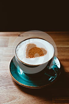 Cup of cappuccino coffee decorated cinnamon heart symbol