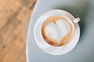 Cup of cappuccino coffee with latte art on gray table in cafe