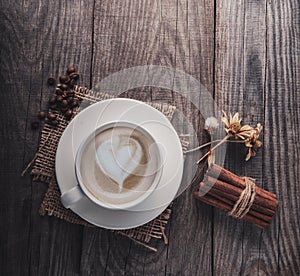 Cup of cappuccino coffee on old vintage wooden table, dry flower , cinnamon, top view