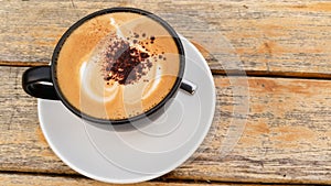 A cup of cappuccino coffee and wood background