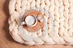 A cup of cappuccino and cookies on the background of blanket of thick yarn. The atmosphere of homeliness and comfort