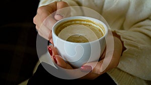 Cup with cappuccino in female hands