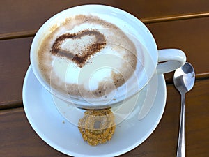 Cup cappuccino with a heart of cocoa decorated milk foam