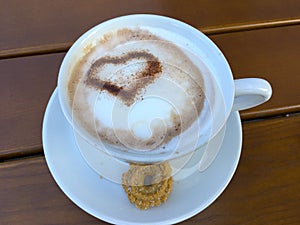 Cup cappuccino with a heart of cocoa decorated milk foam