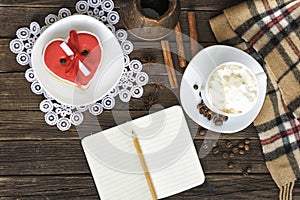 Cup of cappuccino, heart shaped cookies width message, notebook, pencil and coffee pots on a brown wooden table