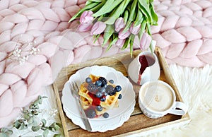 Cup with cappuccino and homemade Belgian waffles with strawberry sauce and berries, pink pastel giant blanket