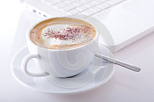 Cup of cappuccino with laptop