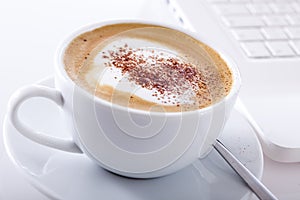 Cup of cappuccino with laptop