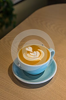Cup with cappuccino or latte with milk foam on wooden table in a cafe or coffeehouse. Simple workspace or coffee break. Blurred