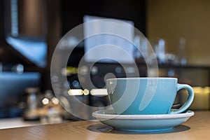 Cup with cappuccino or latte with milk foam on wooden table in a cafe or coffeehouse. Simple workspace or coffee break. Blurred