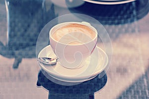 Cup of cappuccino on a saucer with a teaspoon