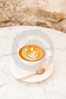 Cup of cappuccino on the white marble table in a modern cafe