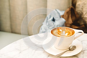 Cup of cappuccino on the white marble table in a modern cafe