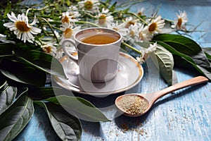 A cup of chamomile tea on a wooden background.