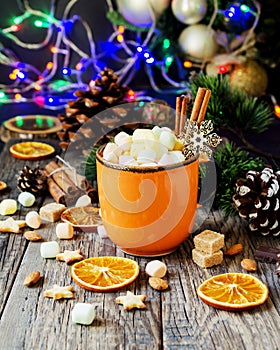 A cup of Christmas hot cocoa with marshmallow New Year`s lights and decorations, selective focus