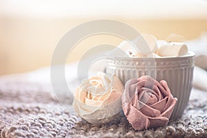 A cup of cocoa or chocolate next to a rose-shaped marshmallow. Warm cozy square background