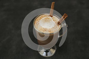 Cup of cocoa or hot chocolate or coffee cappuccino with stick a cinnamon isolated on black background. Top view.