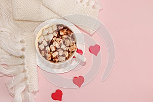 Cup with cocoa and marshmallows, Red hearts and a scarf on a pink background, top view. Holiday greetings, concept of modern woman