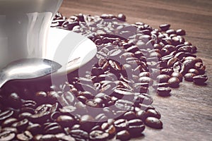 Cup of coffe alongside with coffe beans on the table alongside with spoon