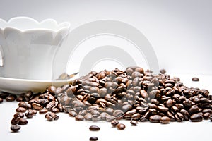 Cup of coffe alongside with coffe beans on white background