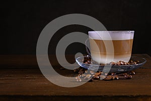 Cup of coffe with milk on a dark background. Hot latte or Cappuccino prepared with milk on a wooden table