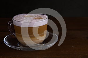 Cup of coffe with milk on a dark background. Hot latte or Cappuccino prepared with milk on a wooden table