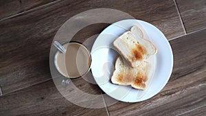 Cup of coffe with milk and two slices of toasted sandwich bread on a white plate. Healthy breakfast with coffee. Top view. Free sp