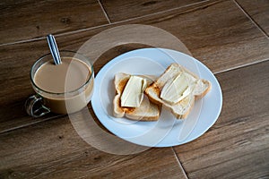 Cup of coffe with milk and two slices of toasted sandwich buttered bread on a white plate. Healthy breakfast with coffee. Side