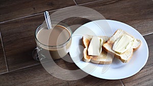 Cup of coffe with milk and two slices of toasted sandwich buttered bread on a white plate. Healthy breakfast with coffee. Side vie