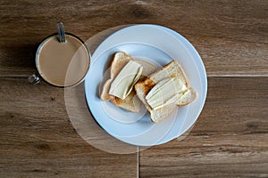 Cup of coffe with milk and two slices of toasted sandwich buttered bread on a white plate. Healthy breakfast with coffee. Top view