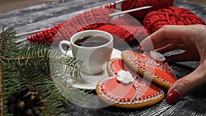 Cup of coffee and 2 red heartshaped ginger-snaps placed on a wooden background near fir tree branches and red yarn with