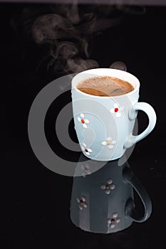 Cup of coffee above black background with reflections