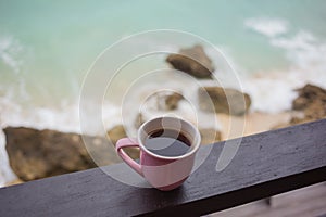 Cup of coffee above blue abyss with ocean waves
