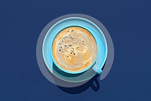 Cup of coffee above view on a blue background. Hot coffee in a blue mug
