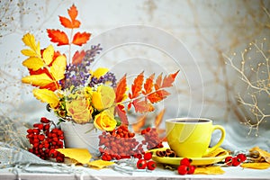 Cup of coffee, autumn leaves and flowers on a wooden table. Autumn still life. Selective focus.