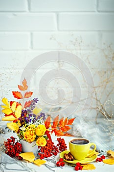 Cup of coffee, autumn leaves and flowers on a wooden table. Autumn still life. Selective focus.