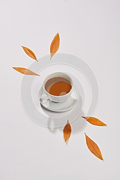 Cup of coffee and autumn leaves on whitte background, top view