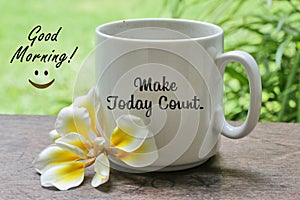 A cup of coffee with Bali frangipani flower on the wooden table with inspirational motivational quote on it - Make today count.