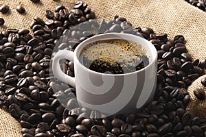 cup of coffee with beans on jute background