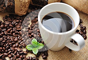 Cup of coffee with beans and leaf