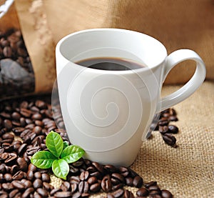 Cup of coffee with beans and leaf.