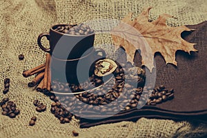 Cup with coffee beans and oak leaf