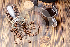 Cup of coffee and beans are scattered from a glass jar