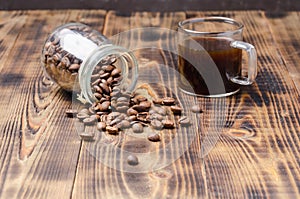 Cup of coffee and beans are scattered from a glass jar