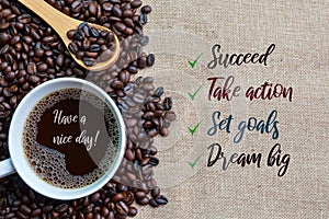 A cup of coffee and coffee beans with text SUCCEED, TAKE ACTION, SET GOALS and DREAM BIG