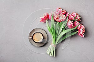 Cup of coffee with beautiful pink flowers for good morning on gray stone table top view in flat lay style. Breakfast on Mother day