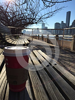 A cup of coffee on the bench with skyline at the background
