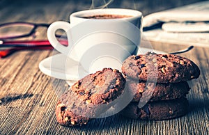 Cup of coffee with biscuit cookies and newspapper. Chocolate biscuit cookies. Chocolate cookies on white linen napkin on wooden ta photo