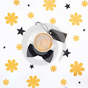 Cup of coffee and black bow tie on white background flat lay. Floral Fathers day still life setup.